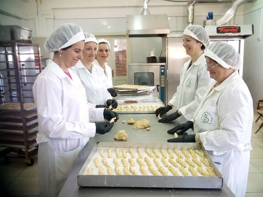 women on the both sides of table and making 'kuluraki' Greek Easter cookies at 'Agrotouristic Women's Cooperative of Mesotopos Lesvos' workshop